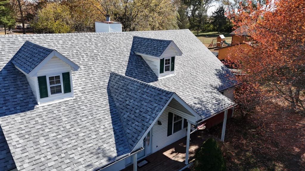 Deb Teno residence — light-gray architectural shingles with dormers, porch roof, and ridge lines from an elevated finished-roof view