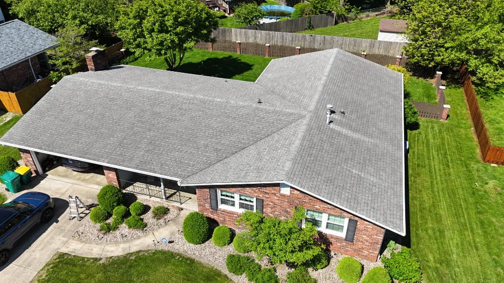 Aerial view of a brick residence — gray roof, white gutters and fascia, siding context and coordinated full exterior envelope