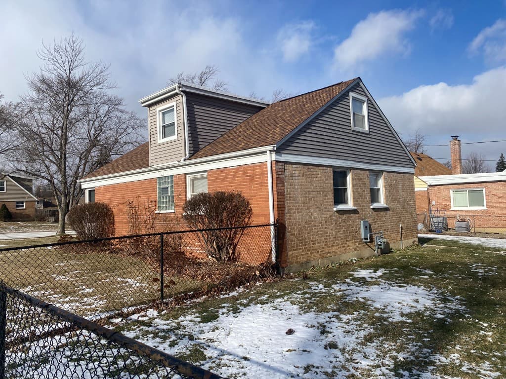 Tim Zolman project — coordinated roof, siding, brick, and gutter integration on a finished residential exterior
