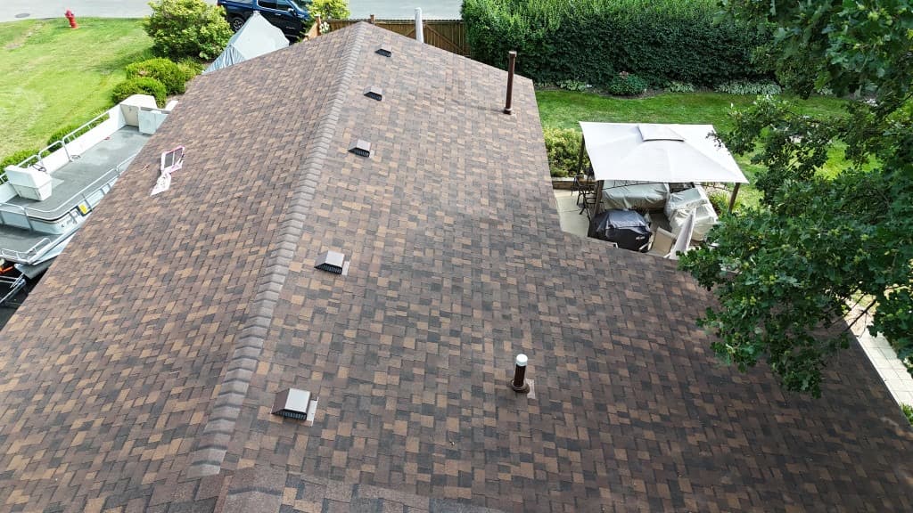 Aerial view of a neatly finished architectural shingle roof with orderly vents and tidy residential property context